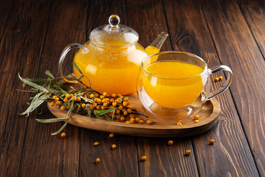 Warm Sea Buckthorn Tea in Glassware with Fresh Berries on Wooden Background