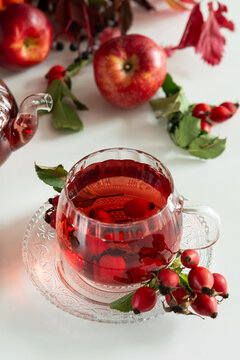 Red fruit tea infusion with apples and rosehips on a white table