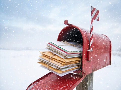 Red mailbox filled with christmas letters and greeting cards in snowy winter weather, representing holiday communication and seasonal tradition.