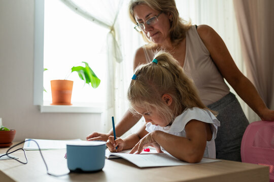 Mother helps daughter with homework at home. Family support, education and positive parenting