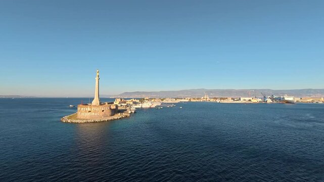 28 April 2026 Italy, Sicily, Strait of Messina, Stele della Madonna della Lettera - timelapse of ship slowly cruising past historic sightseeing monument during sunset