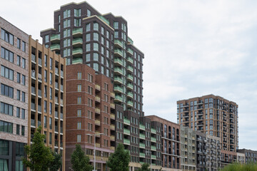 Obraz premium Contemporary apartment buildings with varied brick facades and arched windows along a street in the revitalized residential area of ​​Amsterdam North, the Netherlands.