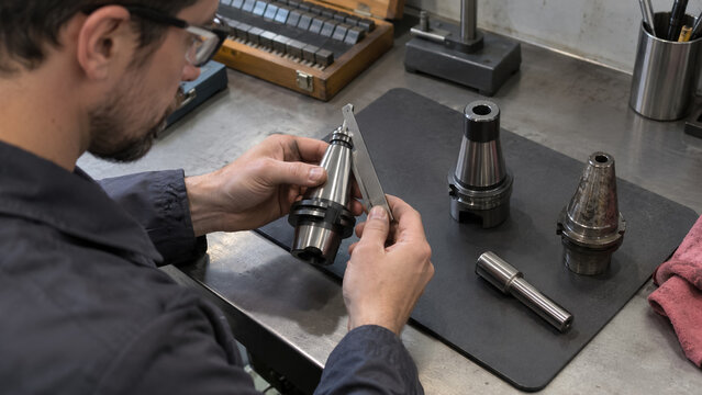 Machinist Inspecting CNC Tool Holder Shank Taper with Gauge in Workshop. Concept of metalworking, inspection, quality control, measuring, precision.