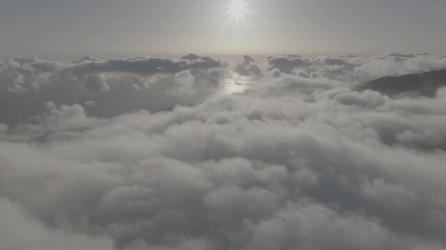 Sunlight illuminates billowing clouds over Madeira, Portugal, in a sweeping drone view (DLOG)