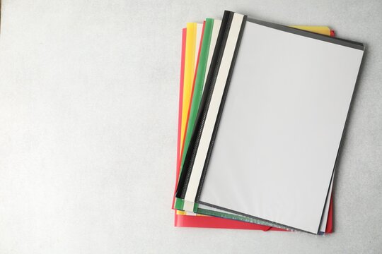 File folders in different colors on light grey textured table, top view. Space for text