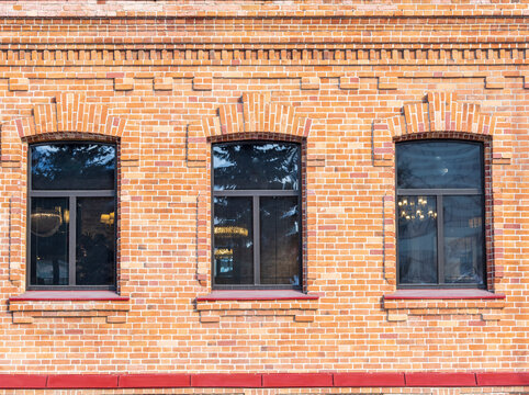 Three windows of the old mansion 19 century with brown bricks wall