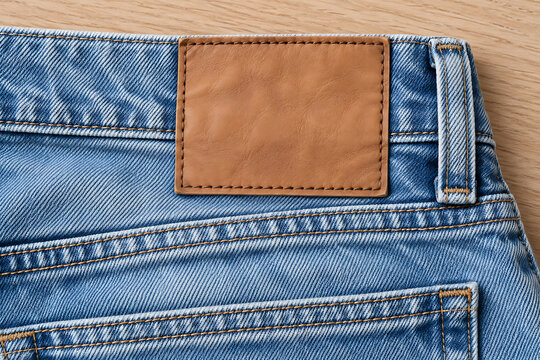 Denim jeans waistband with a brown leather patch detail close up view