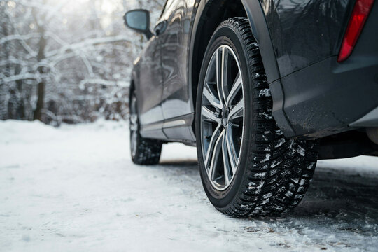 Close-up of a car tire driving on snow-covered road in winter with natural light