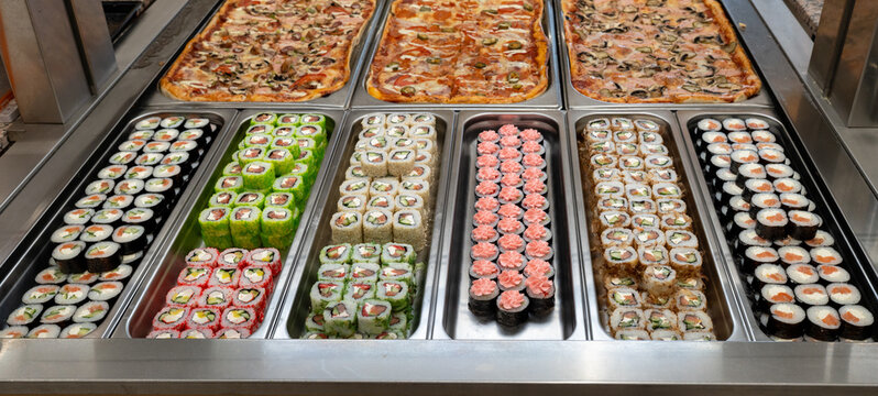 Sushi roll japanese food in grocery store, buffet, or food court. Buying sushi rolls in a store. Japanese food. Various types of sushi rolls on display at a grocery store.