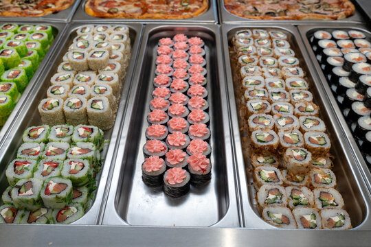 Sushi roll japanese food in grocery store, buffet, or food court. Buying sushi rolls in a store. Japanese food. Various types of sushi rolls on display at a grocery store.