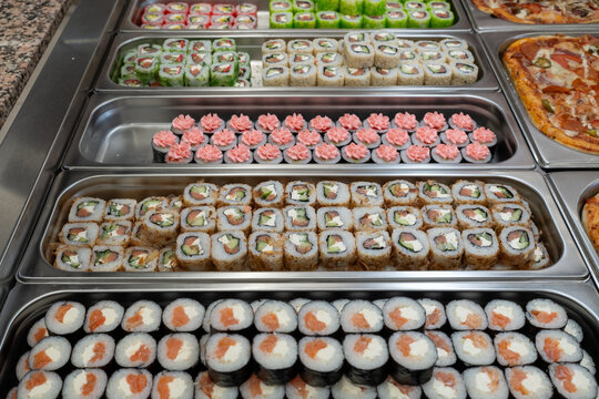 Sushi roll japanese food in grocery store, buffet, or food court. Buying sushi rolls in a store. Japanese food. Various types of sushi rolls on display at a grocery store.