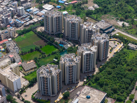 Aerial view of the Hinjewadi Phase III residential complex featuring modern high-rise apartment buildings, a central swimming pool, and surrounding lush greenery in Pune, Maharashtra, India.