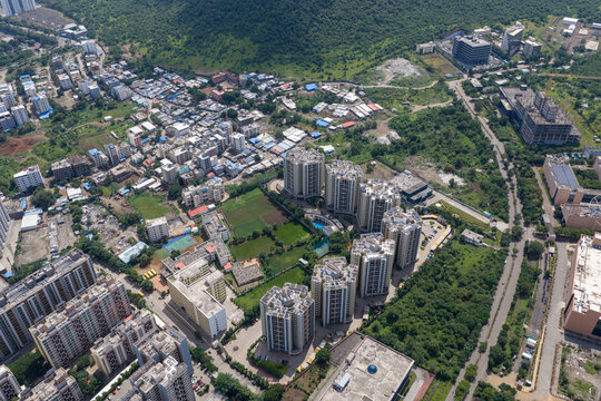 Aerial view of Hinjewadi Phase III showing modern residential apartment complexes, surrounding lush green vegetation, and nearby urban development in Pune, Maharashtra, India.