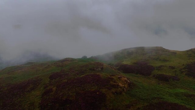 Aerial view of rolling green hills covered in mist, creating a remote and atmospheric landscape.