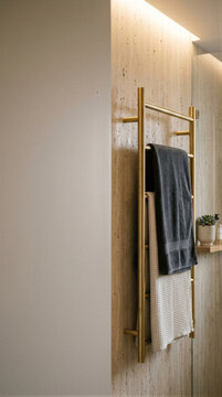 Modern bathroom interior with brass towel rack and folded towels on textured stone wall. Minimal architectural design with warm lighting and copy space for interior design marketing