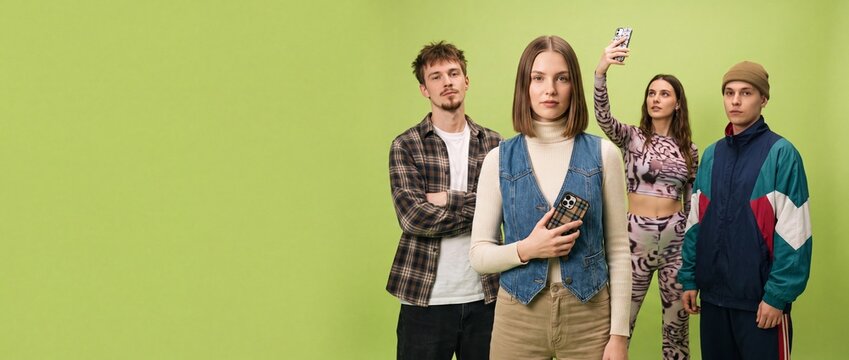 A group of young adults stand against a vibrant green backdrop, each with a distinct expression and style, hinting at individuality and perhaps a collective sentiment of youth culture.