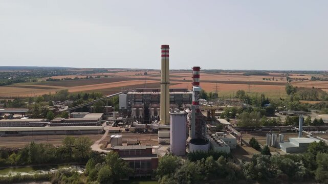 Lake Bokod in Hungary with cooling lake beside the power plant, surrounded by rural fields and forest in summer, industrial energy infrastructure captured in aerial view.