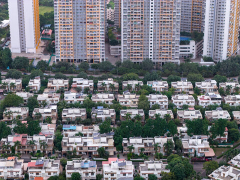 Aerial view of a residential area in Pune, featuring modern high-rise apartment buildings and rows of low-rise houses with lush green trees. Pune, Maharashtra, India.