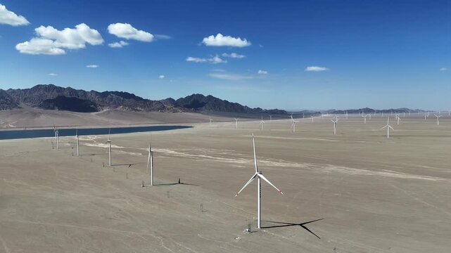 rows of wind turbines in desert landscape with mountains