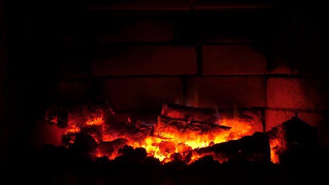 Cozy fireplace warmth illuminates brick hearth as flickering flames dance over stacked logs, revealing ember glow for intimate home evenings indoors winter comfort