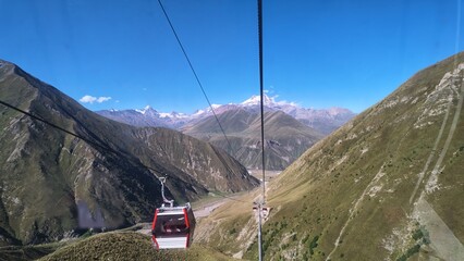 View from a cable car gondola descending through a scenic mountain valley with cables and towers in view © OlenaK