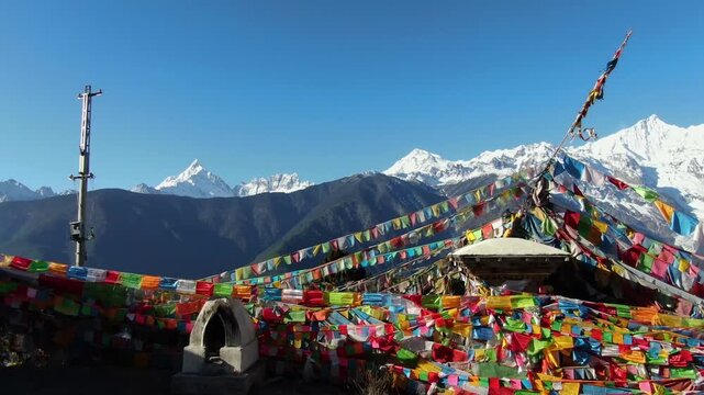 Colorful Buddhist prayer flags and stone stupa with Himalayan mountains and blue sky in Himalayas