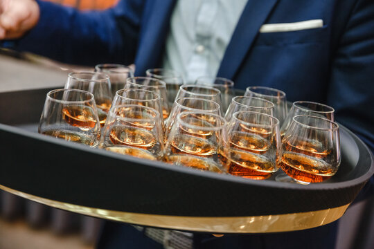 Waiter serving whiskey glasses on tray at event