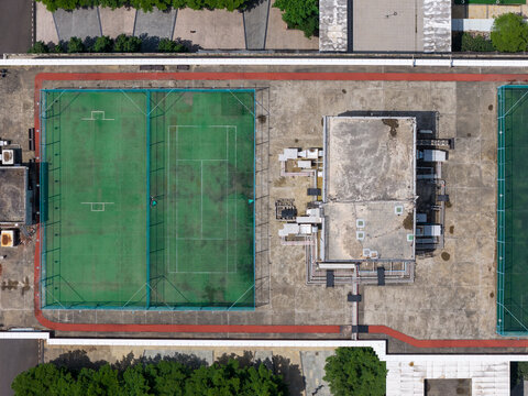 Aerial view of the rooftop sports courts at TCS ITP Cypress, featuring green tennis and futsal courts with a red running track border in Hinjawadi, Maharashtra, India.
