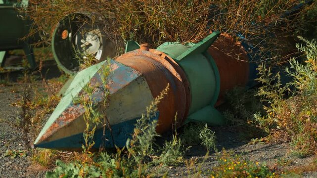 Obsolete, abandoned, and rusty combat missiles and shells stand amidst the natural landscape. A weapons graveyard. An echo of war.