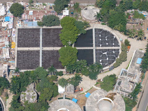 Aerial view of the PCMC Waste Water Treatment Plant featuring circular and rectangular treatment tanks with aeration systems surrounded by lush trees in Pimpri-Chinchwad, Maharashtra, India.