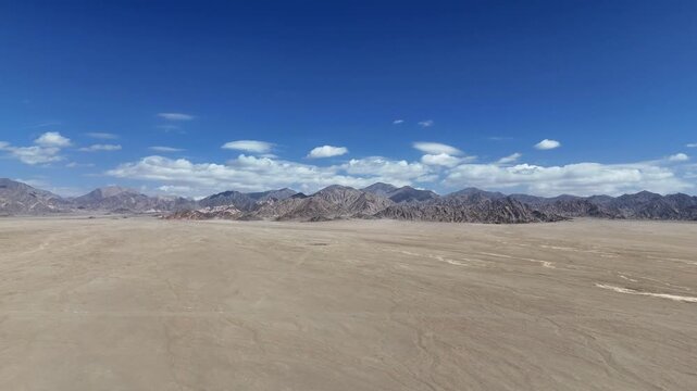 Vast desert landscape extending to distant mountains under a blue sky