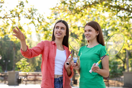 Happy teenage girls with badminton rackets and shuttlecock outdoors