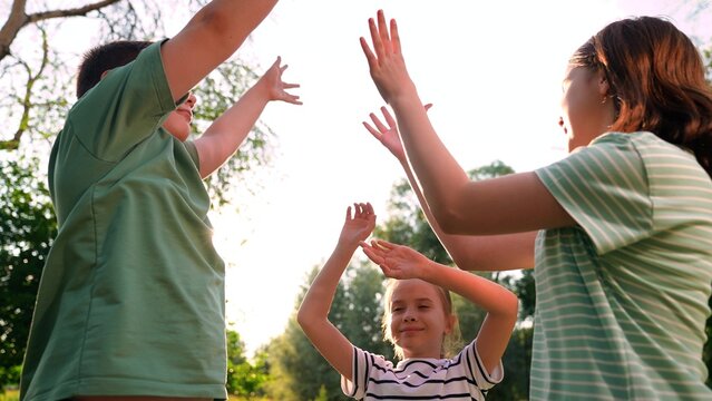 Happy children playing playground, children hands sun glare nature, boy girl friends playground, joyful kids moment captured in natural light, kids playing hand game in a sunlit park, weekend outdoor