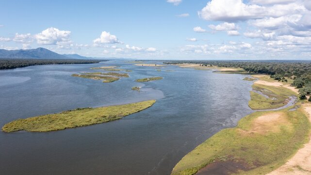 Aerial view of the Zambezi River with lush islands, sandy riverbanks, and distant hills under a clear blue sky in Zimbabwe.