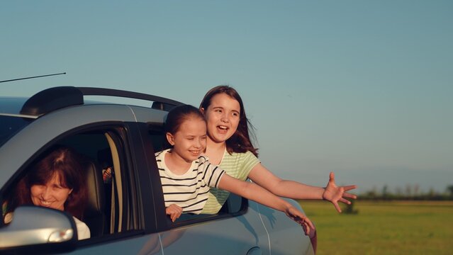 Woman mother child driving car, kid boy girl waving their hands out car window, happy family cheerful people childhood, happy family road trip with kids enjoying sunny countryside breeze, summer road