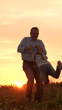 father and daughter playing in field at sunset, family fun outdoors, child swinging with dad, happy childhood moments, nature background with sunset, bonding time together, carefree summer evening