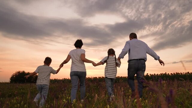 run mother father children boy girl park sunset, man woman toddlers outdoors, Family walking in the field at sunset, Parents and children holding hands outdoors, Happy family time in nature, Summer