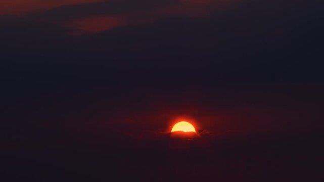 A time‑lapse video showing the orange sun being covered by clouds at sunset.