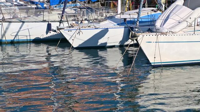 Sailboat bows reflected on rippling marina water