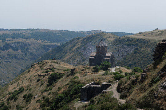 Amberd Fortress stands on a hillside, surrounded by mountains and greenery, highlighting its medieval architecture in the Armenian landscape