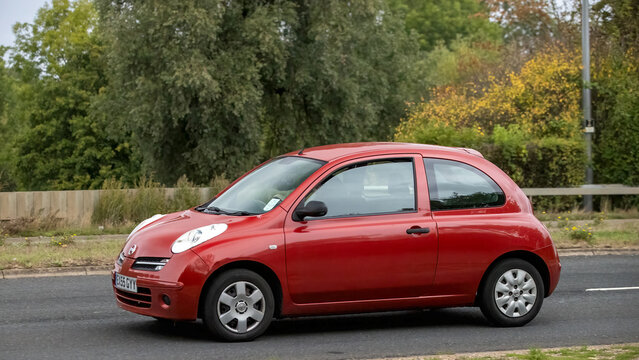 Milton Keynes; UK - Sept. 13th 2026: 2005 red Nissan Micra hatchback car driving on a British road