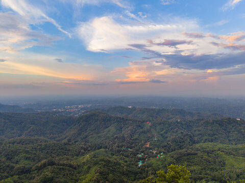 Aerial view of Nilachal hill station surrounded by lush green mountains and dense forests under a vibrant sunset sky in Bandarban District, Chittagong Division, Bangladesh.