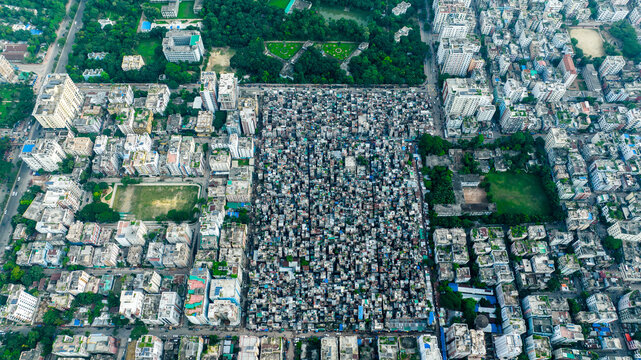 Aerial view of Geneva Camp showing the dense urban layout of the settlement surrounded by multi-story buildings, streets, and green spaces in Dhaka, Dhaka Division, Bangladesh.