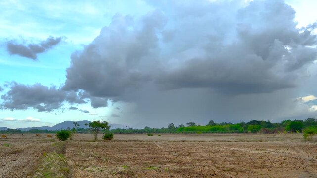 Dramatic Storm Clouds Over Dry Agricultural Fields and Distant Mountains