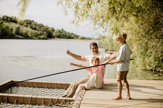 Father and children enjoy fishing together by a serene lakeside