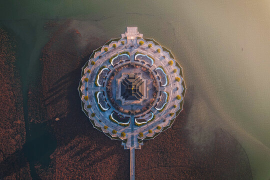 Aerial view of the circular Chongyuan Temple surrounded by water with a long bridge leading to the entrance in Suzhou, Jiangsu, China.