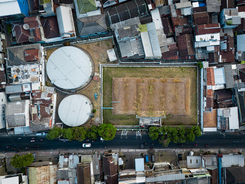 Aerial view of Tandon Air BETEK PDAM KOTA MALANG, a historic colonial-era water storage facility with circular tanks and a rectangular reservoir, in Malang, East Java, Indonesia.