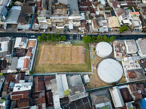 Aerial view of the historic Tandon Air Betek water storage facility with circular tanks and rectangular reservoir, set among dense urban rooftops in Malang, East Java, Indonesia.
