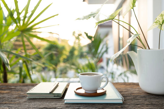 White coffee cup and plant pot and notebook at balcony outdoor