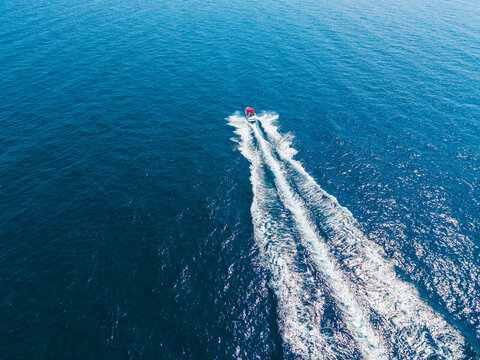 Boat traveling across the blue ocean water leaving a wake behind in a sunny day